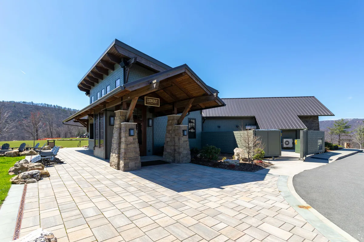 The welcoming entrance of a community lodge, complete with stone pillars, an entrance awning, and a paved walkway. This spot often serves as a gathering place for community events and sets the tone for hospitality and shared experiences.