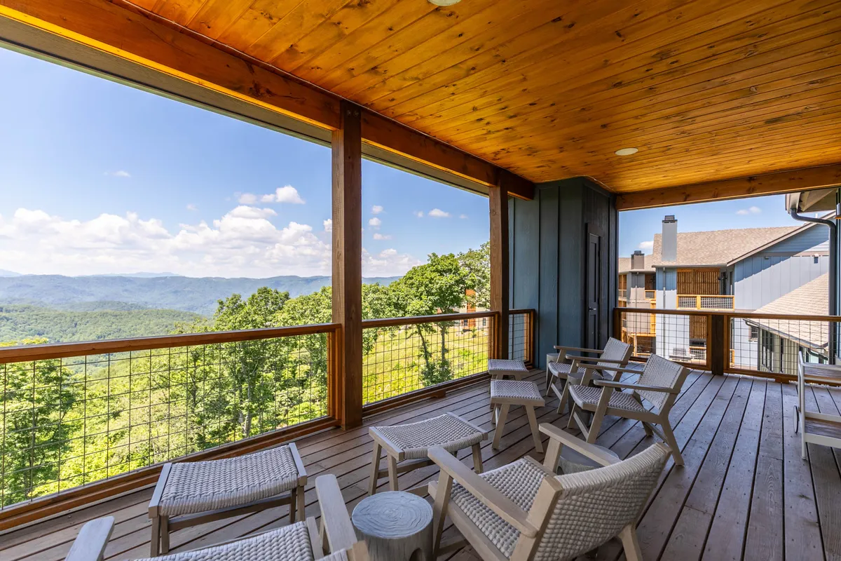 An inviting wooden deck with comfortable seating is perched to capture panoramic mountain views. The tranquil environment encourages relaxation, social gatherings, and appreciation of nature, seamlessly blending the privacy of a luxury home with the allure of the mountain landscape.