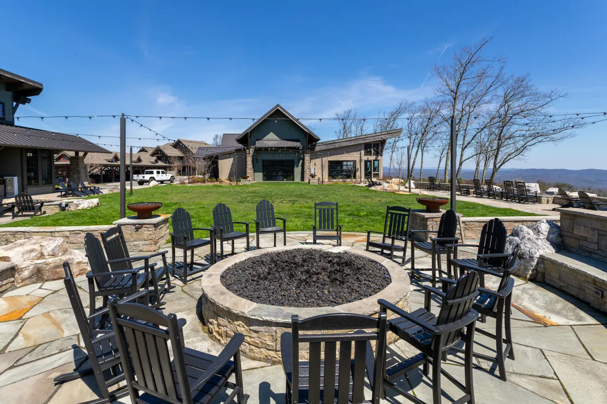 A gathering area with a fire pit, comfortable seating, landscaped lawn, and panoramic mountain views. The warm communal vibe suggests evenings spent sharing stories or enjoying the scenery together after a day of exploration.